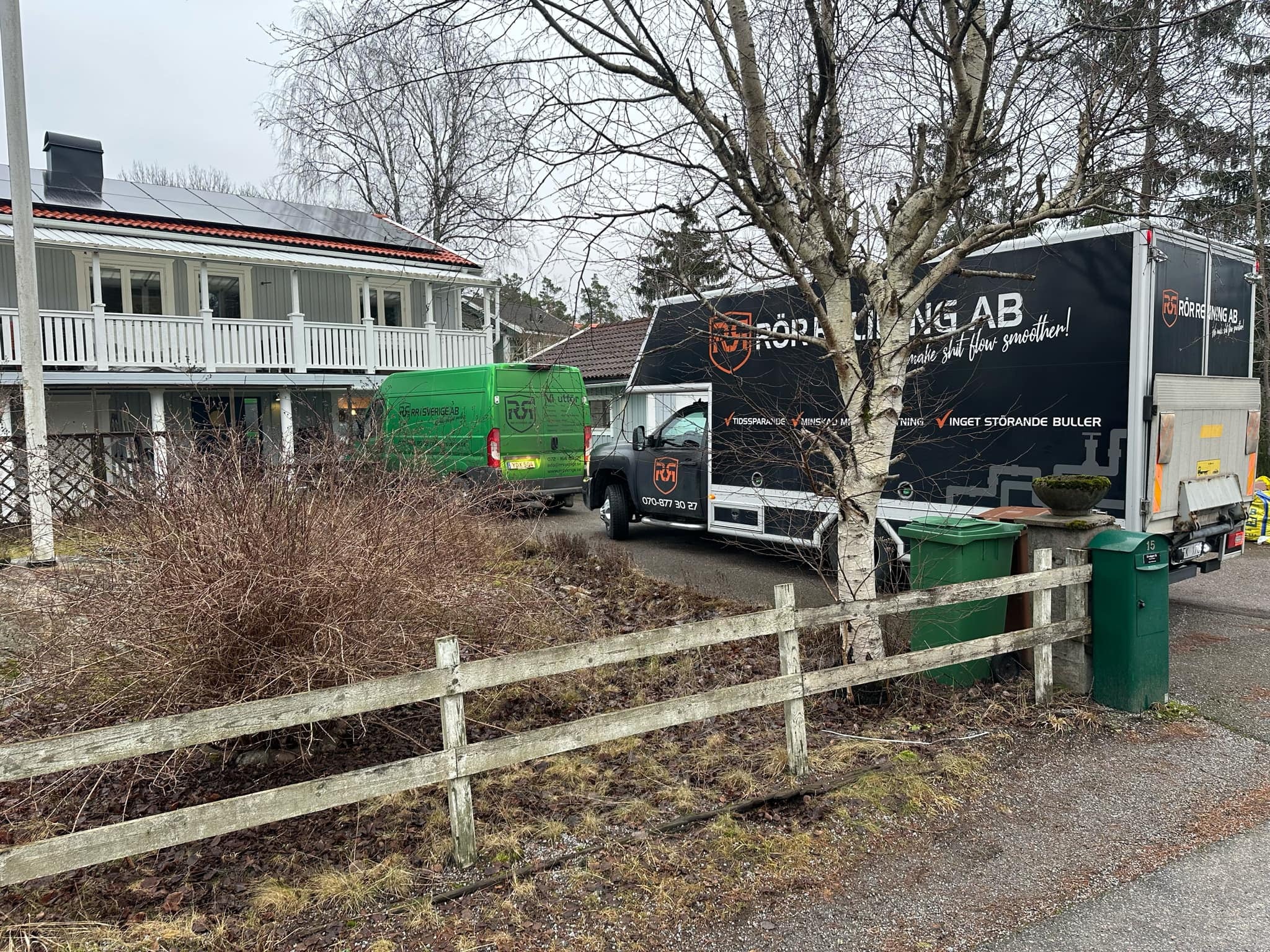 RR Syd servicebil och svart lastbil parkerade vid staket i Älta, redo för avloppsinspektion och relining
